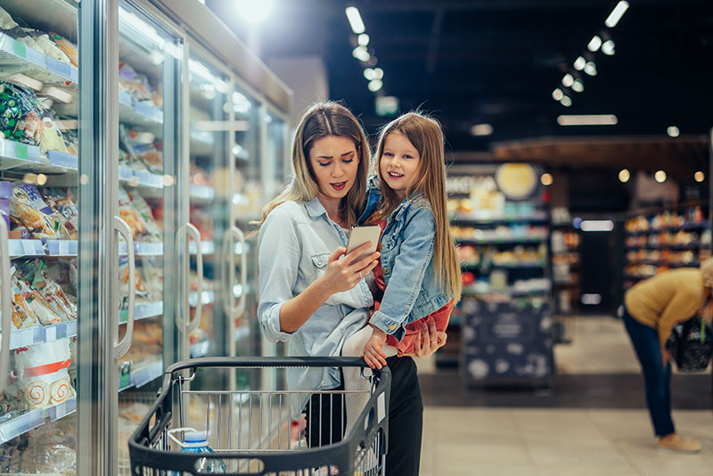 Mother in super market holding child while on the phone